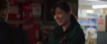 Movie still from “A Good Woman Is Hard to Find” (2019), directed by Abner Pastoll – A woman smiles while holding a cell phone; Close Up shot, Over the shoulder angle