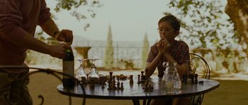 Movie still from “A Good Year” (2006), directed by Ridley Scott – A man sitting at a table with a chess set; Medium shot, Over the shoulder angle