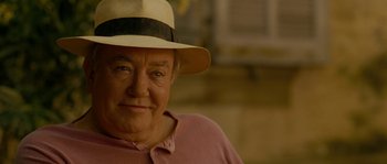 Movie still from “A Good Year” (2006), directed by Ridley Scott – An older man wearing a white hat and a pink shirt; Close Up shot, Over the shoulder angle