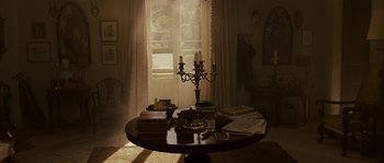 Movie still from “A Good Year” (2006), directed by Ridley Scott – A table in a living room with books and a candle holder; Wide shot, High angle