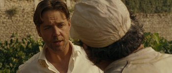 Movie still from “A Good Year” (2006), directed by Ridley Scott – A man standing next to another man wearing a turban; Close Up shot, Over the shoulder angle