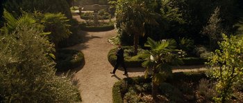 Movie still from “A Good Year” (2006), directed by Ridley Scott – A man in a suit walking down a path in the middle of a garden; Extreme Wide shot, High angle