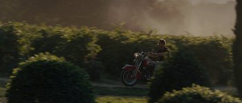 Movie still from “A Good Year” (2006), directed by Ridley Scott – A man riding a motorcycle down a dirt road; Extreme Wide shot, Low angle