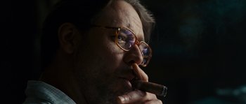 Movie still from “A Good Year” (2006), directed by Ridley Scott – A person wearing glasses and holding a cigar; Close Up shot, Low angle