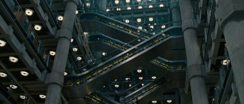 Movie still from “A Good Year” (2006), directed by Ridley Scott – Several escalators in a building with lights on them; Extreme Wide shot, Overhead angle