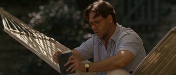 Movie still from “A Good Year” (2006), directed by Ridley Scott – A man sitting on a bench looking at a book; Medium shot, Low angle