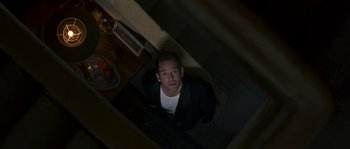 Movie still from “A Good Year” (2006), directed by Ridley Scott – A man standing on the bottom of a staircase; Medium shot, Overhead angle