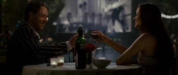 Movie still from “A Good Year” (2006), directed by Ridley Scott – Two people are toasting with wine at a table; Medium shot, Over the shoulder angle