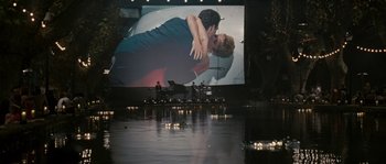 Movie still from “A Good Year” (2006), directed by Ridley Scott – A large screen showing a man and a woman kissing; Extreme Wide shot, High angle