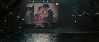 Movie still from “A Good Year” (2006), directed by Ridley Scott – A couple kissing in front of a large screen; Extreme Wide shot, Over the shoulder angle