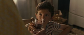 Movie still from “A Good Year” (2006), directed by Ridley Scott – A young boy drinking a glass of wine; Close Up shot, Over the shoulder angle