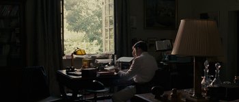 Movie still from “A Good Year” (2006), directed by Ridley Scott – A man sitting at a desk in front of a window; Wide shot, Over the shoulder angle