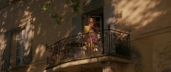 Movie still from “A Good Year” (2006), directed by Ridley Scott – A woman standing on a balcony holding a basket; Wide shot, Low angle