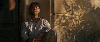 Movie still from “A Good Year” (2006), directed by Ridley Scott – A man sitting on the ground in front of a brick wall; Medium shot, Low angle
