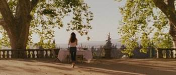 Movie still from “A Good Year” (2006), directed by Ridley Scott – A woman standing in front of a table with a view; Wide shot, Over the shoulder angle