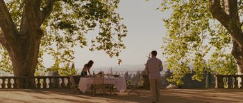 Movie still from “A Good Year” (2006), directed by Ridley Scott – Two women are sitting at a table outside; Extreme Wide shot, Over the shoulder angle
