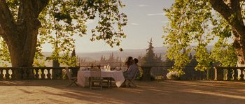 Movie still from “A Good Year” (2006), directed by Ridley Scott – A man and a woman sitting at a dinner table; Extreme Wide shot, High angle
