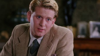 Movie still from “A Handful of Dust” (1988), directed by Charles Sturridge – A person wearing a suit and tie; Close Up shot, Over the shoulder angle