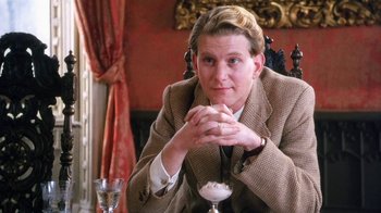 Movie still from “A Handful of Dust” (1988), directed by Charles Sturridge – A woman sitting at a table with a glass of milk; Close Up shot, Over the shoulder angle