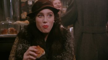 Movie still from “A Handful of Dust” (1988), directed by Charles Sturridge – A woman in a fur coat and hat eating a sandwich; Close Up shot, Over the shoulder angle