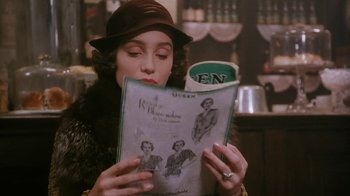 Movie still from “A Handful of Dust” (1988), directed by Charles Sturridge – A woman in a hat reading a magazine; Close Up shot, Over the shoulder angle