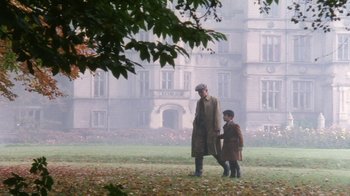 Movie still from “A Handful of Dust” (1988), directed by Charles Sturridge – A man and a boy standing in front of a building; Wide shot, High angle