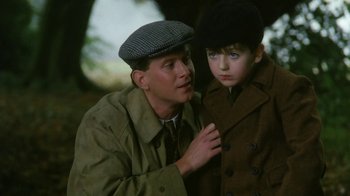 Movie still from “A Handful of Dust” (1988), directed by Charles Sturridge – A man and a boy wearing hats and coats; Close Up shot, Over the shoulder angle