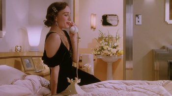 Movie still from “A Handful of Dust” (1988), directed by Charles Sturridge – A woman sitting on a bed talking on a phone; Medium shot, High angle