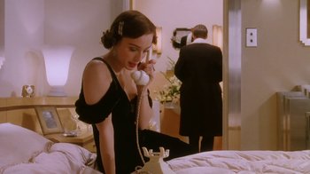 Movie still from “A Handful of Dust” (1988), directed by Charles Sturridge – A woman talking on a phone while a man takes a picture of it; Medium shot, High angle