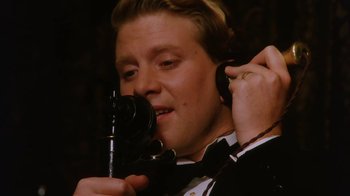 Movie still from “A Handful of Dust” (1988), directed by Charles Sturridge – A man in a tuxedo is holding a camera and taking a picture; Close Up shot, Low angle