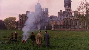 Movie still from “A Handful of Dust” (1988), directed by Charles Sturridge – A group of people standing in front of an old building; Extreme Wide shot, High angle