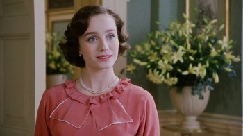Movie still from “A Handful of Dust” (1988), directed by Charles Sturridge – A woman in a pink dress standing in front of a vase of flowers; Close Up shot, Over the shoulder angle