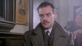 Movie still from “A Handful of Dust” (1988), directed by Charles Sturridge – A man with a mustache wearing a coat and tie; Close Up shot, Low angle