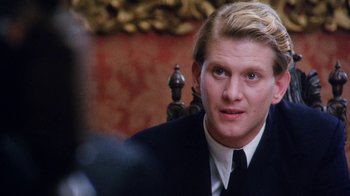 A man in a suit sitting in front of a camera