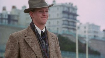 Movie still from “A Handful of Dust” (1988), directed by Charles Sturridge – A man wearing a hat and a coat and a scarf; Medium shot, Low angle