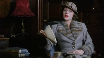 Movie still from “A Handful of Dust” (1988), directed by Charles Sturridge – A woman sitting in a chair holding a book in her hands; Medium shot, Low angle