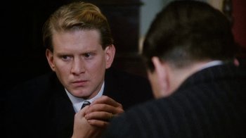 Movie still from “A Handful of Dust” (1988), directed by Charles Sturridge – A man looking at himself in the mirror while wearing a tie; Close Up shot, Over the shoulder angle