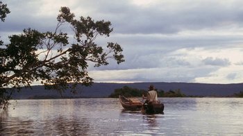 Movie still from “A Handful of Dust” (1988), directed by Charles Sturridge – Two people in a boat on a body of water; Extreme Wide shot, Low angle