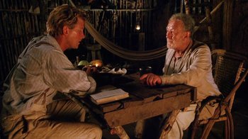 Movie still from “A Handful of Dust” (1988), directed by Charles Sturridge – Two men sitting at a table in a room; Medium shot, High angle