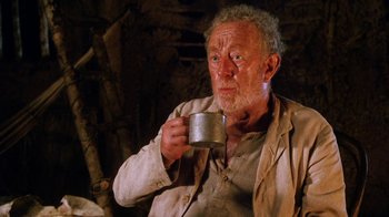 Movie still from “A Handful of Dust” (1988), directed by Charles Sturridge – An older man holding a cup of coffee; Close Up shot, Low angle