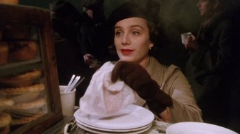 Movie still from “A Handful of Dust” (1988), directed by Charles Sturridge – A woman sitting at a table with a plate in front of her; Close Up shot, Low angle