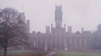 Movie still from “A Handful of Dust” (1988), directed by Charles Sturridge – A large building with a clock on the top of it; Extreme Wide shot, High angle