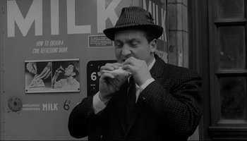 Movie still from “A Hard Day's Night” (1964), directed by Richard Lester – A black and white photo of a man eating a sandwich; Medium shot, Low angle