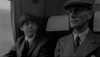 Movie still from “A Hard Day's Night” (1964), directed by Richard Lester – A man and a boy sitting next to each other on a train; Close Up shot, Over the shoulder angle