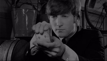 Movie still from “A Hard Day's Night” (1964), directed by Richard Lester – A young man holding a deck of playing cards; Close Up shot, High angle