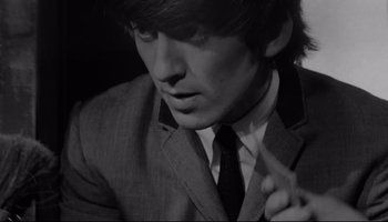 Movie still from “A Hard Day's Night” (1964), directed by Richard Lester – A man in a suit and tie smoking a cigarette; Close Up shot, High angle