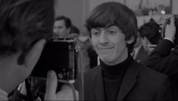 Movie still from “A Hard Day's Night” (1964), directed by Richard Lester – A young man in a black jacket and a camera; Close Up shot, Over the shoulder angle