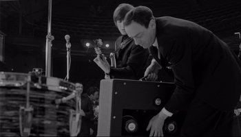 Movie still from “A Hard Day's Night” (1964), directed by Richard Lester – A man in a black suit and a man in a black suit and a man in a black suit and a man in a black suit; Medium shot, High angle
