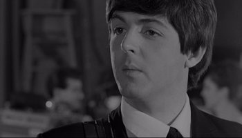 Movie still from “A Hard Day's Night” (1964), directed by Richard Lester – A black - and - white photo of a man in a suit and tie; Close Up shot, Over the shoulder angle