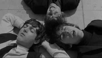 Movie still from “A Hard Day's Night” (1964), directed by Richard Lester – Two young men laying on the ground with their heads together; Close Up shot, Overhead angle